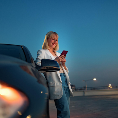 Kobieta stojąca obok samochodu z telefonem w dłoni